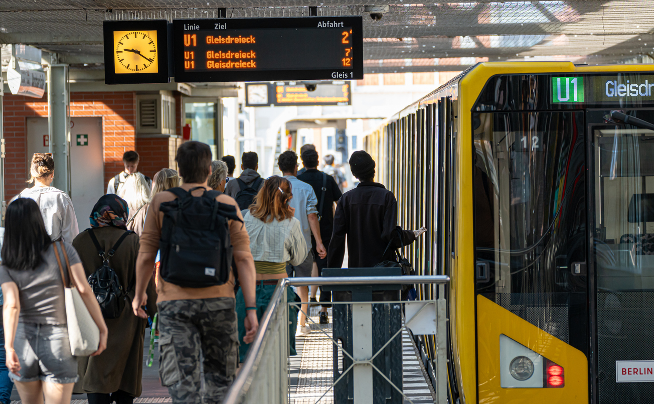 Rückansicht von Menschen an der U-Bahn-Station Warschauer Straße neben einer U-Bahn
